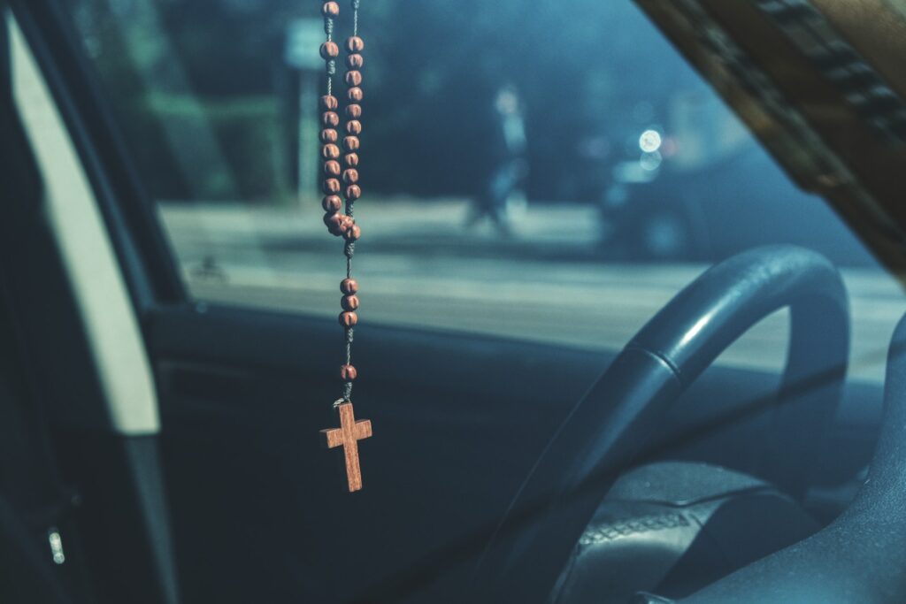 Brown Rosary Dangling on Car's Rear View Mirror