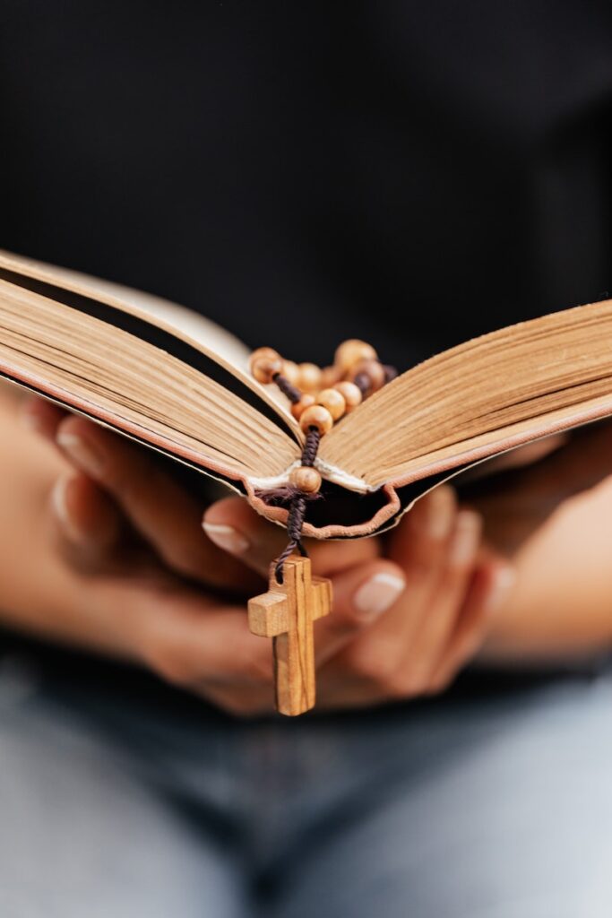 Close-Up Shot of a Person Reading a Book with Rosary